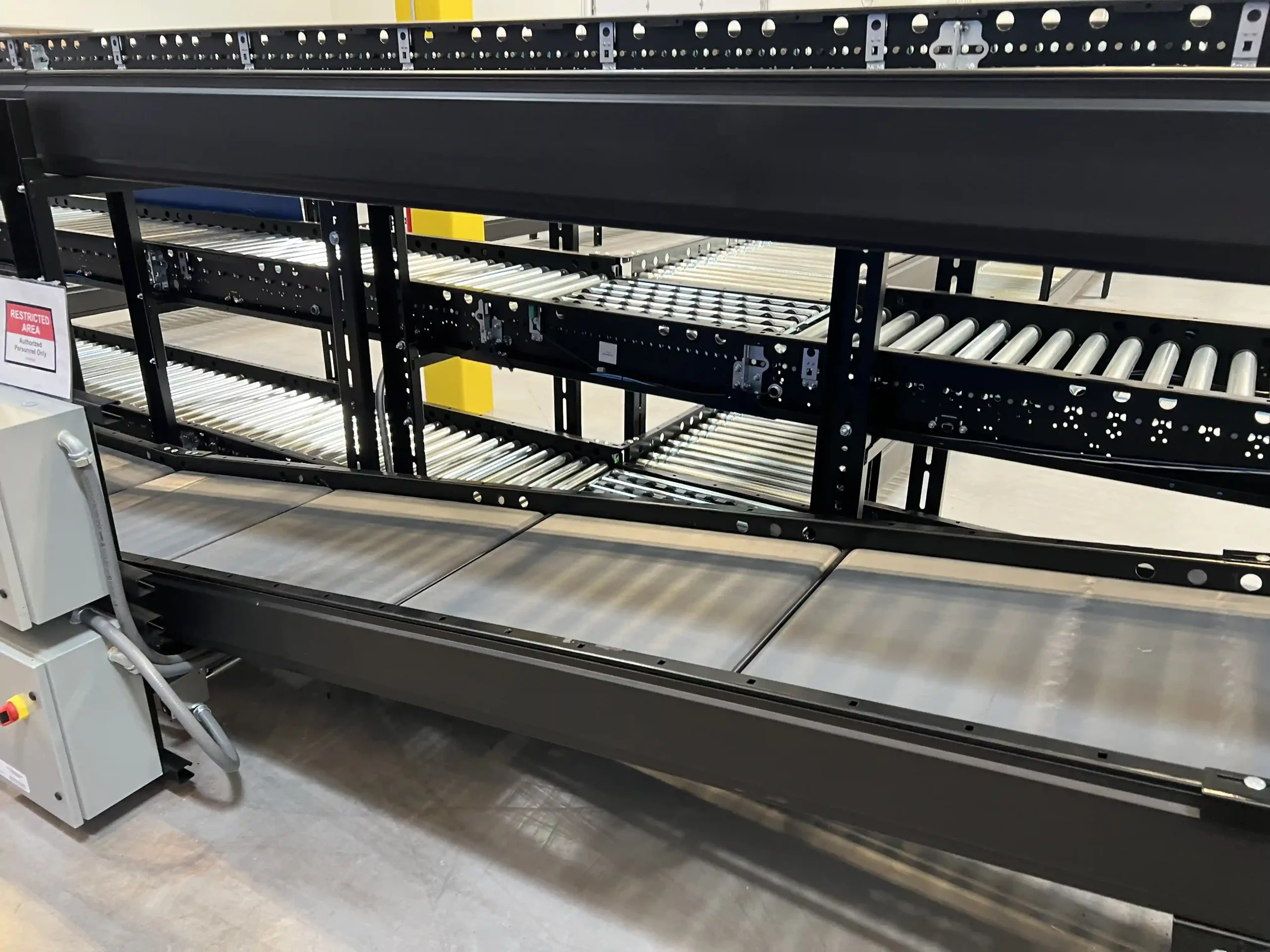 A conveyor belt moving up from the floor level to a level that is three feet high. There is a second conveyor system with three levels in the background.