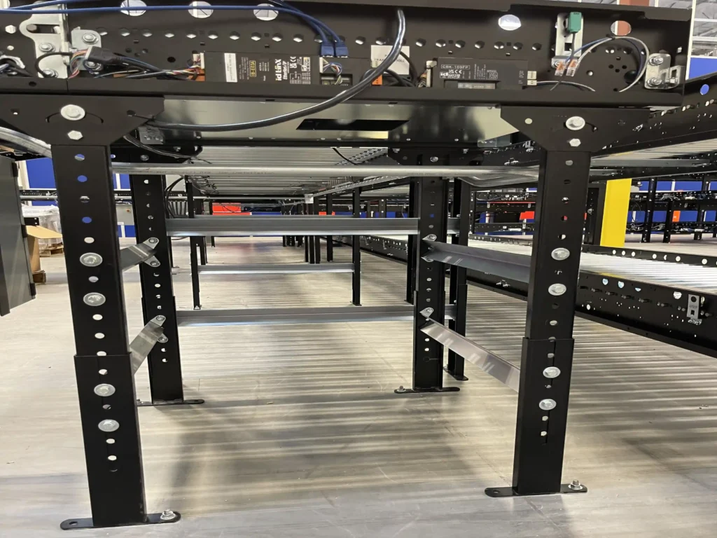 Side view looking up to a conveyor system showing the underside of a conveyor.